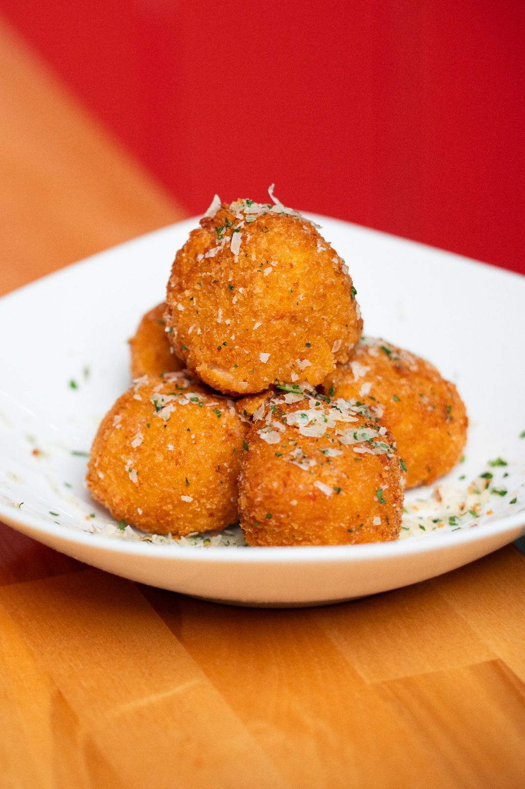 A plate of crisp arancini topped with grated Parmigiano