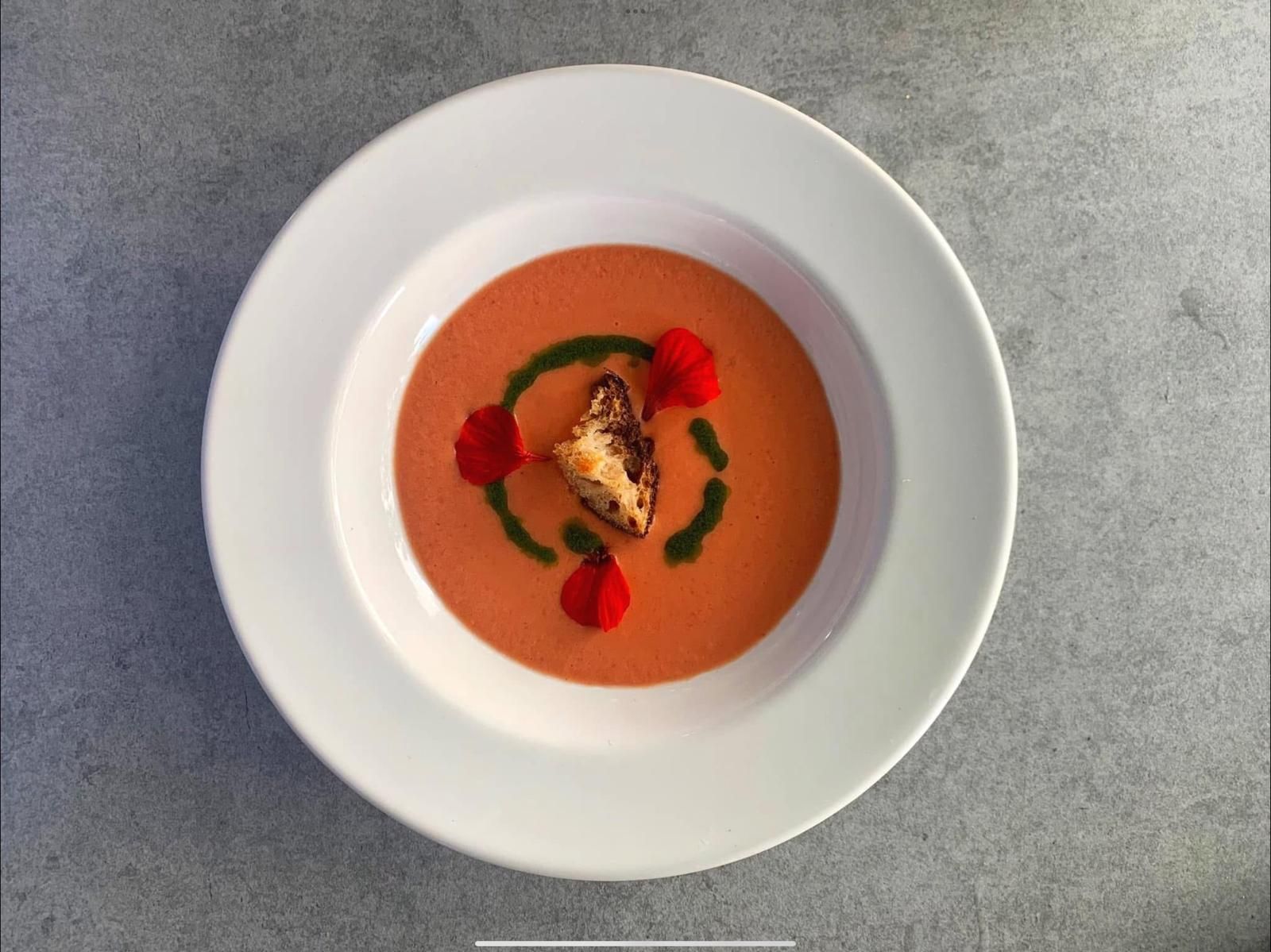 Chilled tomato soup with a crouton, basil oil and edible flowers (opens Rosolini on Instagram)